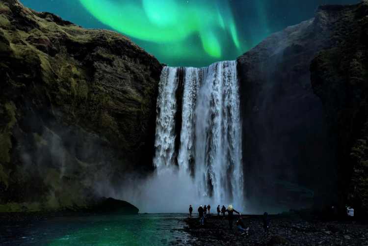 Skógafoss waterfall on the South Coast of Iceland with northern lights in the background.